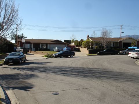 1991 Ford Taurus - A residential street scene with several cars parked in driveways and on the street.