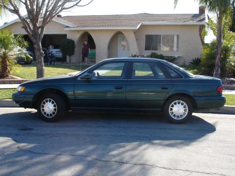 1991 Ford Taurus - Side profile of a 1991 Ford Taurus sedan parked on a residential street.