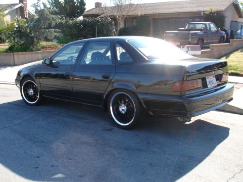 1991 Ford Taurus - A black 1991 Ford Taurus sedan is shown from a three-quarter front angle on a sunny day.