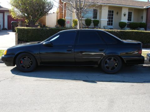 1991 Ford Taurus - Side view of a black 1991 Ford Taurus sedan parked on a residential street.