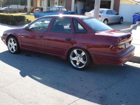 1991 Ford Taurus - This 1991 Ford Taurus sedan is shown from a 3q-front angle, custom chrome wheels and a maroon paint job.