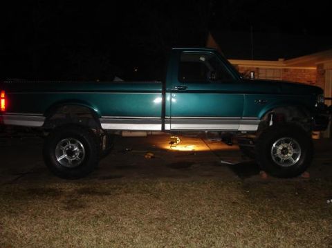 1996 Ford F-150 - Side view of a lifted 1996 Ford F-150 pickup truck parked outdoors at night.