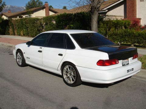 1991 Ford Taurus - This 1991 Ford Taurus is seen from the rear 3/4 angle, a white body and a contrasting black trunk lid.