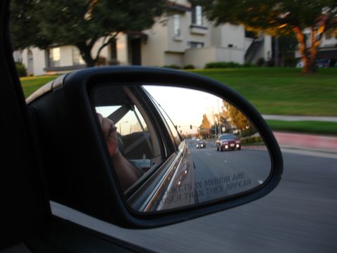 1991 Ford Taurus - Traffic viewed in the side mirror of a car during sunset.