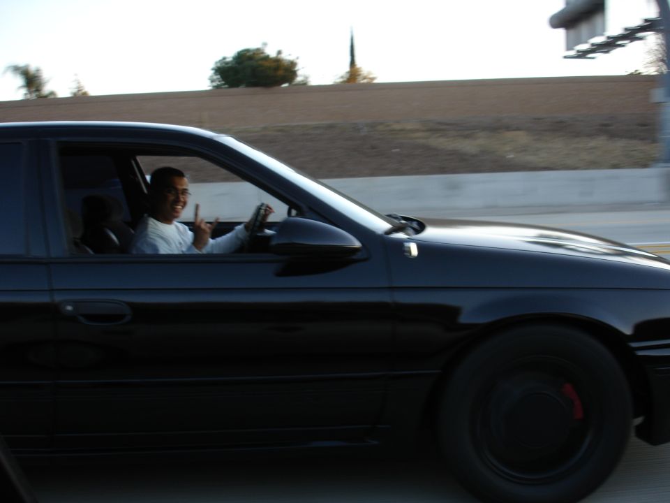 Black sedan side view with driver giving peace sign