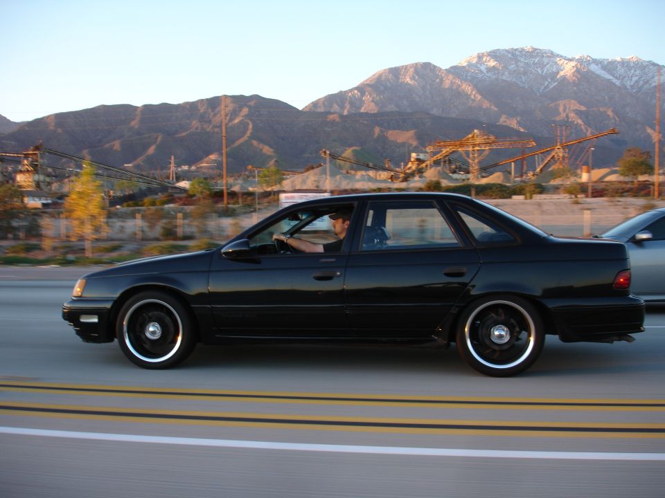 1991 Ford Taurus driving on highway with mountains in background