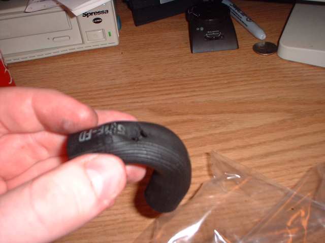Hand holding a black rubber hose with embossed text '03-346'. Hose has a damaged section