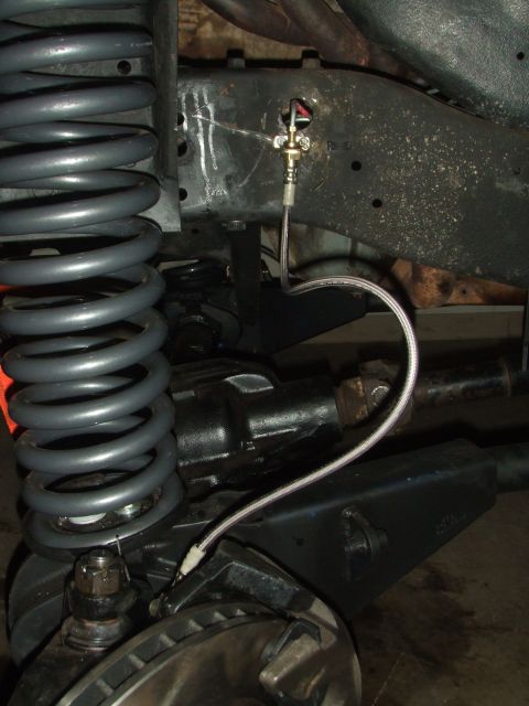 1996 Ford Bronco - Detail of suspension and brake system components, including a braided hose and coil spring.