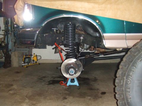 1996 Ford Bronco - The front suspension of a 1996 Ford Bronco is shown with the wheel off and the vehicle on a jack stand.
