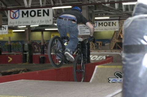 1997 Ford Probe - Indoor bicycle ramp with a rider performing a stunt. MOEN signs are visible in the background.