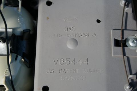 1996 Ford Bronco - This photo shows a close-up of a gray plastic part with embossed Ford branding and various part numbers.