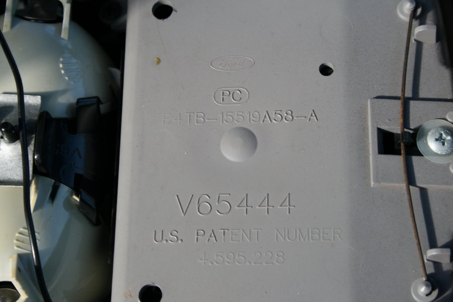 Close-up of a gray plastic part with Ford logo and part numbers like F4TB-15519A58-A and V65444