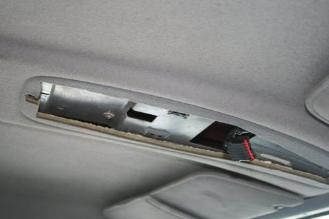 1996 Ford Bronco - The overhead console of a 1996 Ford Bronco shows exposed wiring and a metal mounting bracket.