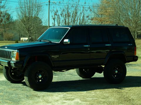 1989 Jeep Cherokee - This black Jeep Cherokee is shown with a lifted suspension and aftermarket wheels, suggesting modifications for off-road use.