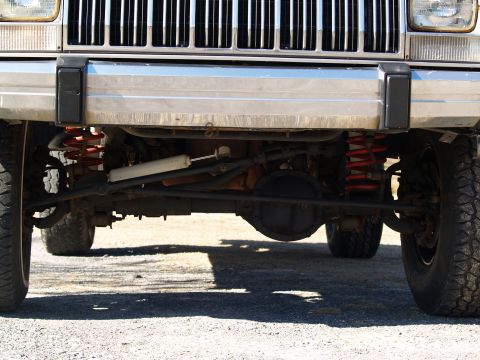 1989 Jeep Cherokee - Close-up of the front suspension and grille of a Jeep Cherokee, highlighting its off-road modifications.