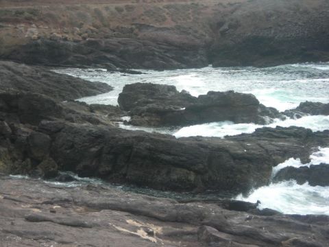 1988 Ford Bronco - Waves crash against rocks on a coastline. The image includes a watermark for Supermotors.net.