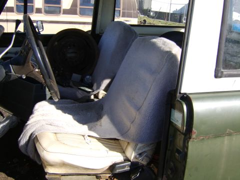 1986 Ford Ranger - The interior of a vehicle shows worn seats and a steering wheel, with a rolled-up item behind the driver's seat.