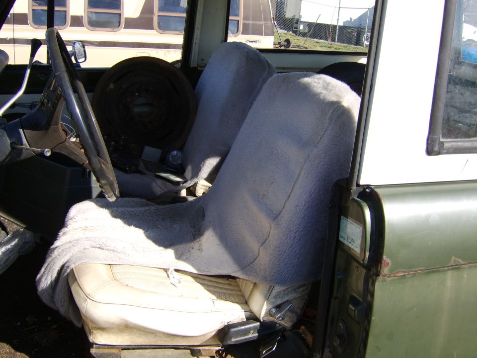 Interior view of a vehicle with two front seats covered in fuzzy grey material. Steering wheel and dashboard visible