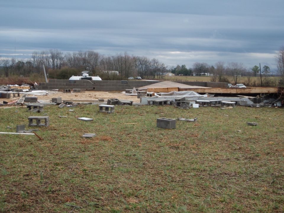 Storm-damaged building site with scattered cinder blocks and collapsed wood decking
