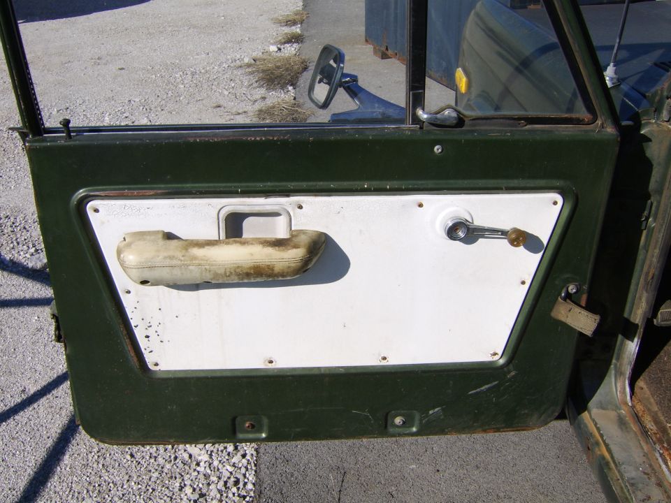 Door panel with armrest, window crank, and door handle. Exterior shows dark green paint