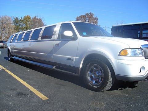 1991 Ford Crown Victoria - A white limousine is parked on an asphalt lot under a clear blue sky.