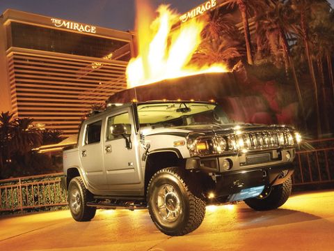 1991 Ford Crown Victoria - A Hummer H2 SUT is parked outside The Mirage hotel at night, with flames shooting up from behind the building.