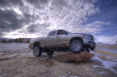 1991 Ford Crown Victoria - A lifted Dodge Ram pickup truck is positioned on a large rock with a dramatic cloudy sky overhead.