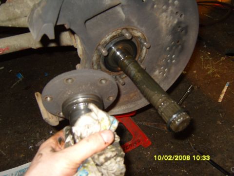 1989 Ford Bronco - Close-up of a greasy vehicle spindle and hub assembly being cleaned with a rag.