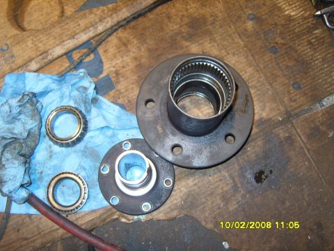 1989 Ford Bronco - Disassembled spindle bearings and hub assembly parts are laid out on a workbench.