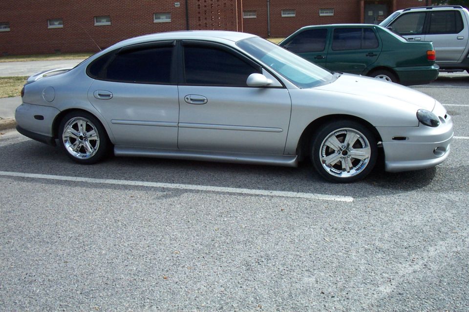 Silver Ford Taurus sedan side view on chrome wheels with body kit