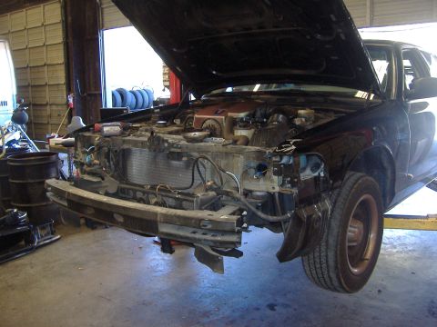 2001 Ford Crown Victoria - Front end of a black 2001 Ford Crown Victoria is disassembled for repairs in a garage.