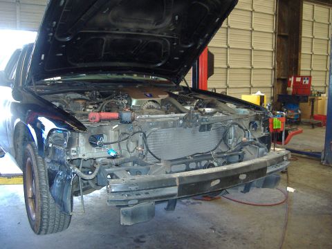2001 Ford Crown Victoria - Vehicle in a repair shop with the front bumper removed and hood open, showing the engine and radiator.
