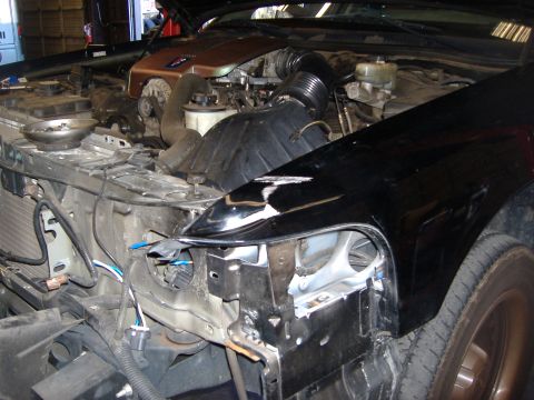 2001 Ford Crown Victoria - The front end of a car is disassembled, revealing the engine and various mechanical parts.
