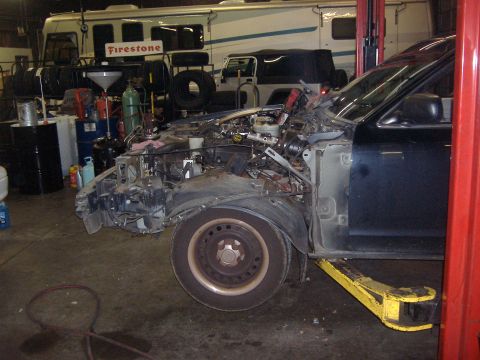 2001 Ford Crown Victoria - Front end of a 2001 Ford Crown Victoria with extensive damage, undergoing repairs.