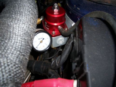 1994 Ford Probe - Close-up view of a red fuel pressure regulator and gauge, part of an engine's fuel system.