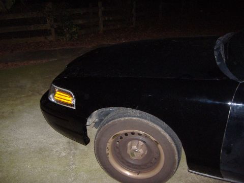 2001 Ford Crown Victoria - Front corner of a black 2001 Ford Crown Victoria, showing the headlight and fender.