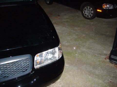2001 Ford Crown Victoria - A black sedan is parked in a lot, with another vehicle visible in the background.