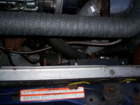 1994 Ford Probe - Close-up view of turbocharger components and heat-wrapped piping in an engine bay.