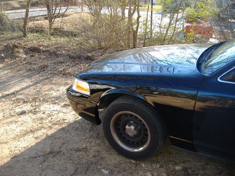 2001 Ford Crown Victoria - Front fender and wheel of a black sedan, consistent with a 2001 Ford Crown Victoria.