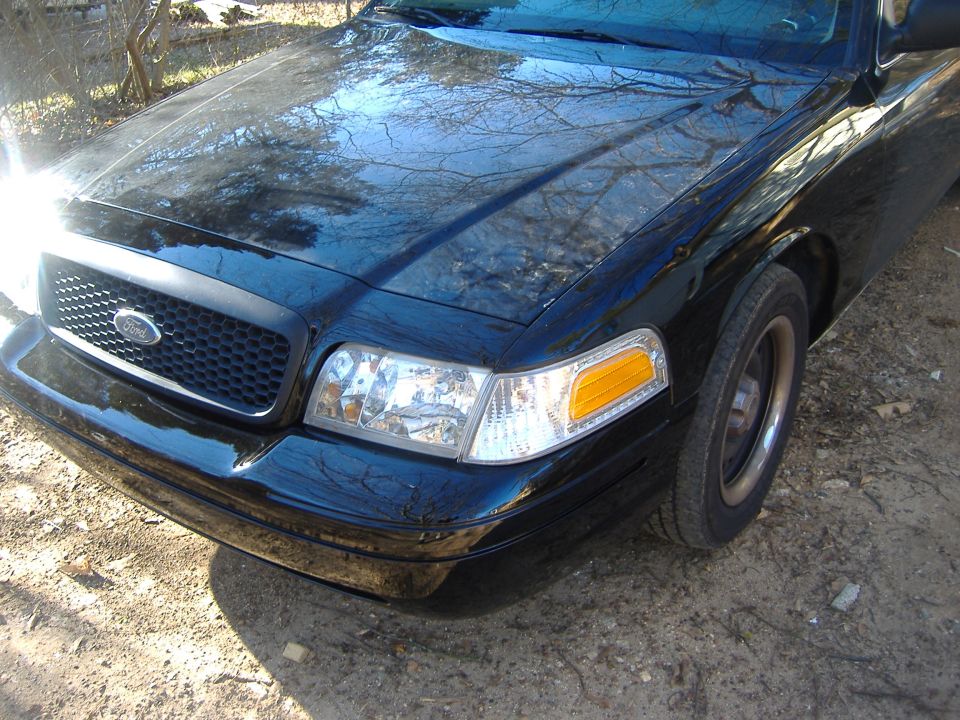 Front corner of a black 2001 Ford Crown Victoria with a honeycomb grille and clear headlights