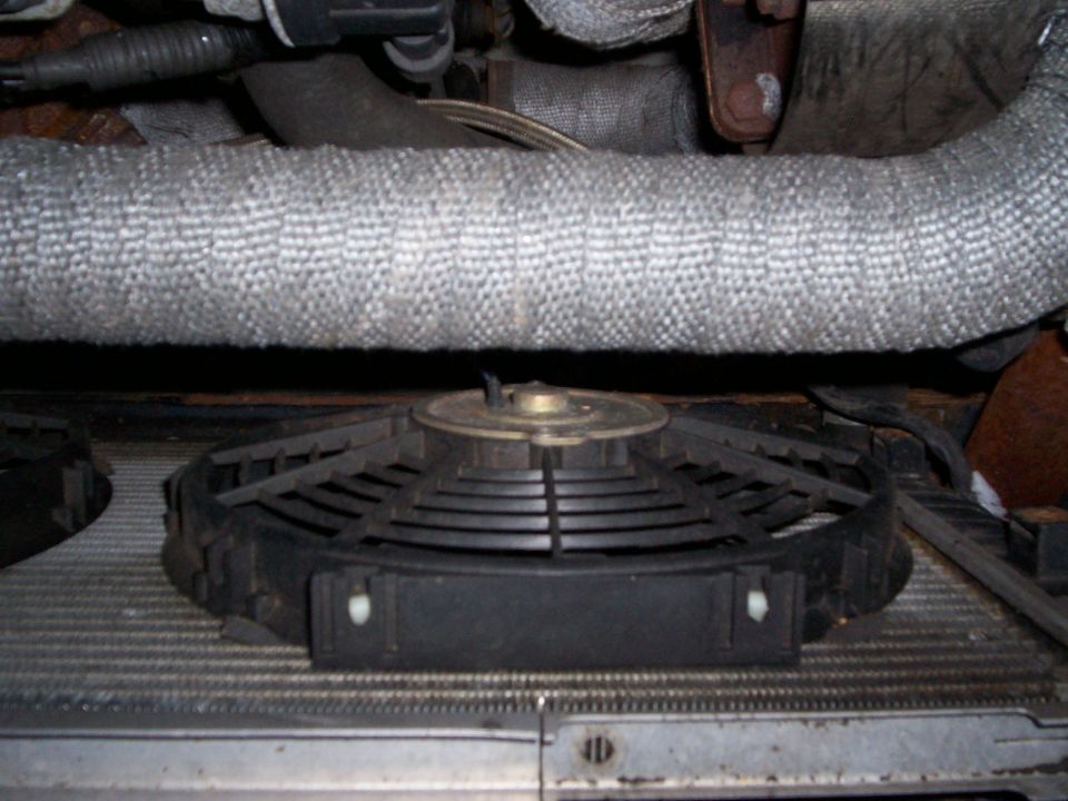 Close-up of a car's radiator fan and some insulated engine hoses