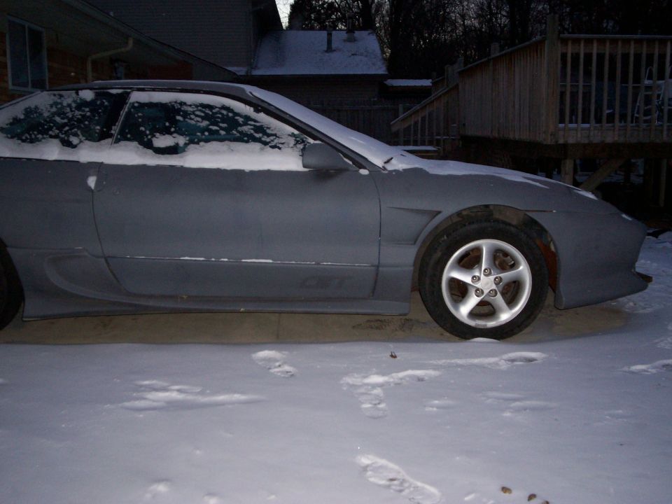 1994 Ford Probe in primer, covered in snow, parked outside