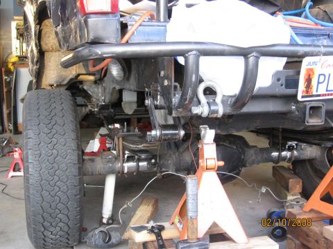 1994 Ford Bronco - The rear suspension and custom bumper assembly of a vehicle are visible, supported by jack stands.