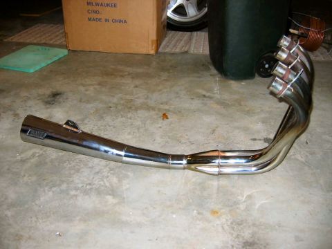 1985 Ford LTD Crown Victoria - Chrome motorcycle exhaust pipe with four header pipes. Text on muffler reads 'MARCY'.