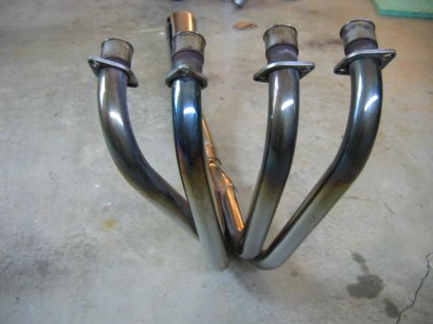 1985 Ford LTD Crown Victoria - Exhaust header pipes for a motorcycle or similar vehicle, shown on a concrete floor.