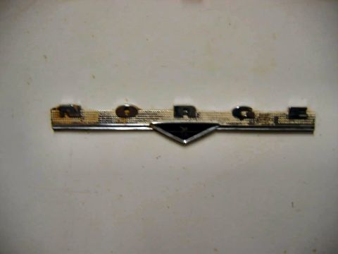 1985 Ford LTD Crown Victoria - A close-up shows a chrome badge with the letters N, O, R, A, G, E, set against a white background.