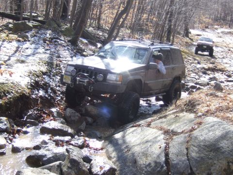 1976 Toyota Land Cruiser - A Jeep Grand Cherokee tackles a challenging off-road course with another vehicle in pursuit.
