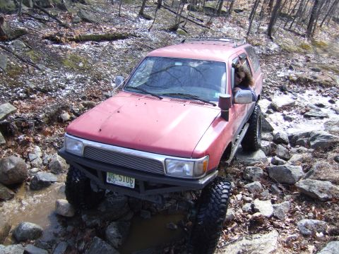 1976 Toyota Land Cruiser - This vehicle is navigating a challenging off-road course with large rocks and water obstacles.