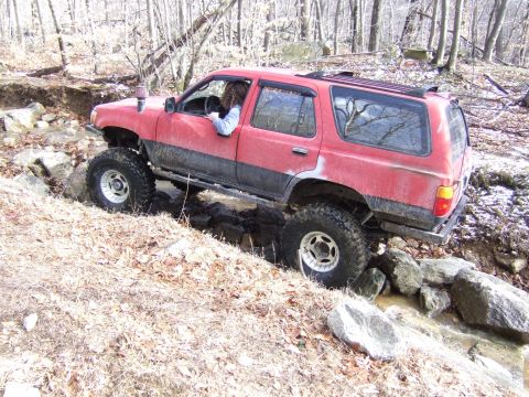 1976 Toyota Land Cruiser - This red SUV is shown navigating a challenging off-road course with large tires and a lifted suspension.