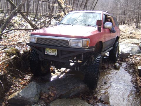 1976 Toyota Land Cruiser - Modified Toyota 4Runner navigates a challenging off-road course with water and rocks.